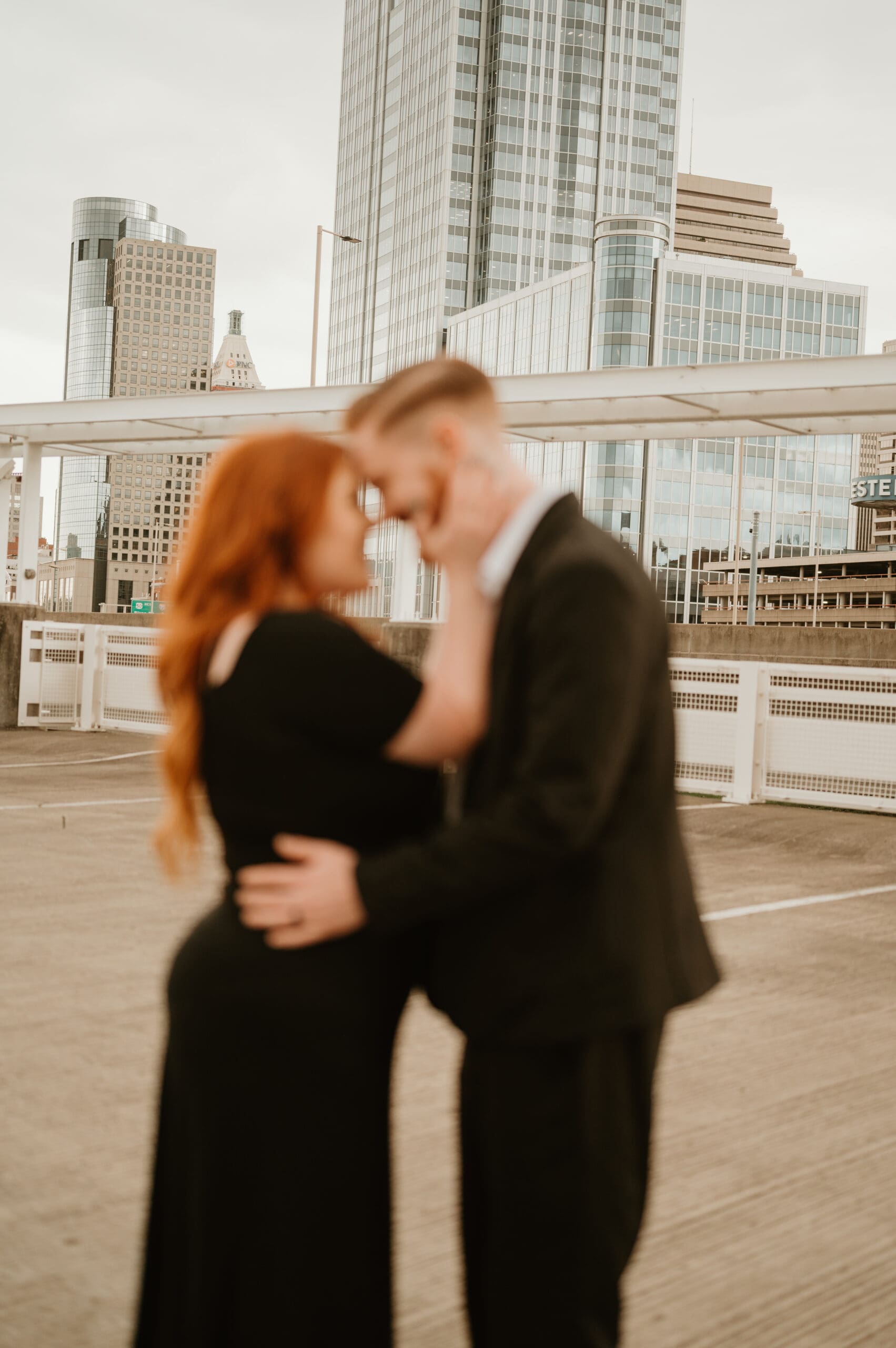 Engaged couple embracing on a Cincinnati rooftop during overcast sunset